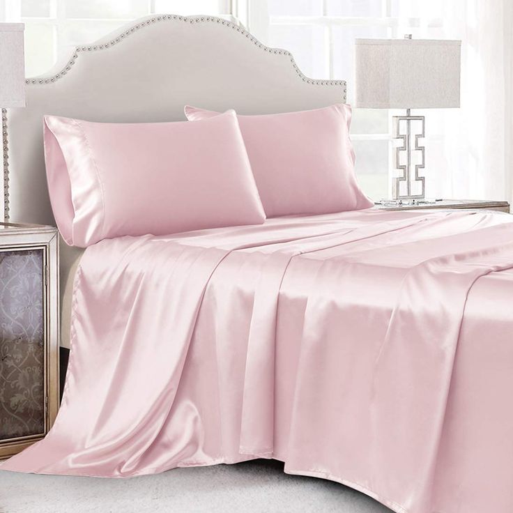 a bed covered in pink sheets and pillows