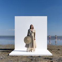 a woman standing in front of a white backdrop on the beach