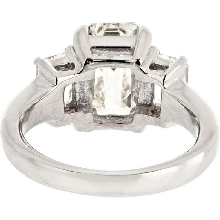 Relish in the sophistication of fine artistry and avant-garde design with our breathtaking 3 Carat Emerald Cut Diamond Three Stone Engagement Ring. This exquisite piece exudes timeless elegance and modern allure, making it a perfect choice for discerning individuals seeking a symbol of everlasting love and commitment.Crafted with precision, the centerpiece of this ring features a mesmerizing 3.15-carat emerald-cut diamond, certified by GIA with a J color grade and VS1 clarity, ensuring exceptional quality and brilliance. Flanking this stunning center stone are two equally mesmerizing emerald-cut diamonds totaling 1.15 carats, adding a captivating symmetry and luxurious appeal to the design.Encased in lustrous platinum, this ring boasts a substantial metal weight of 9.1 grams, reflecting it Luxury Round Cut Polished Diamond Ring, Luxury Round Cut Diamond Ring With Polished Finish, Modern Moissanite Wedding Ring With Center Stone, Modern Platinum Rings For Gift, Modern Platinum Rings For Gifts, Modern Polished Finish Rings For Anniversary, Luxury Wedding Diamond Ring With Polished Finish, Timeless White Gold And Platinum Jewelry, Luxury Polished Diamond Ring For Wedding