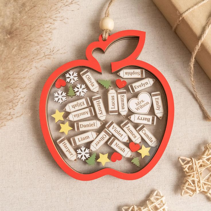 an ornament shaped like an apple with words on it and snowflakes