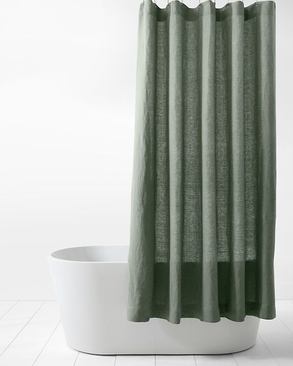 a green shower curtain hanging on the side of a bathtub