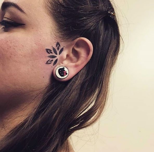 a woman with black and white tattoos on her ear