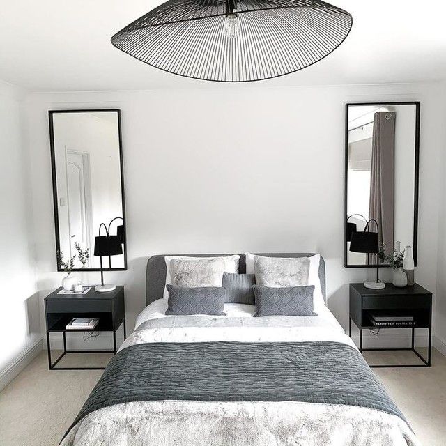 a bedroom with white walls and grey bedding