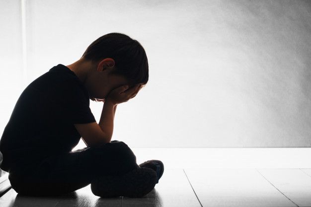 a young boy sitting on the floor with his head in his hands