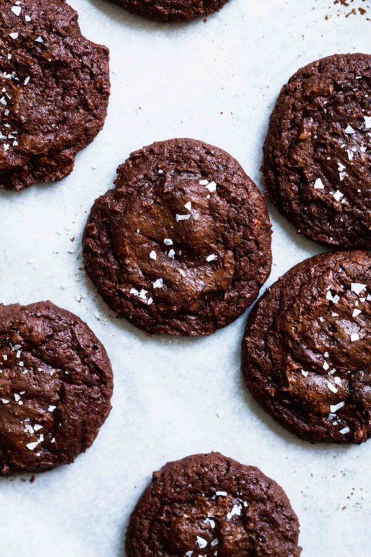 chocolate cookies with sea salt and flecks are on a baking sheet, ready to be eaten