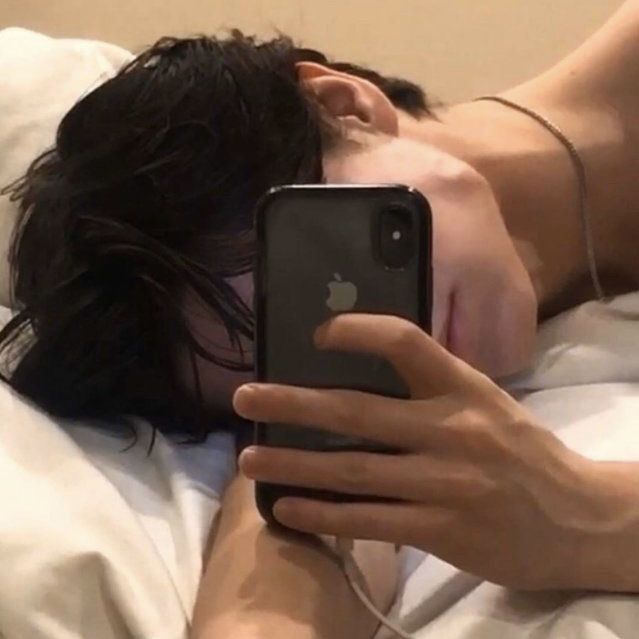 a person laying in bed with their cell phone up to their face while they are sleeping