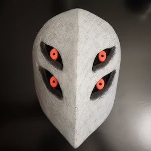 a white mask with red eyes and two black holes