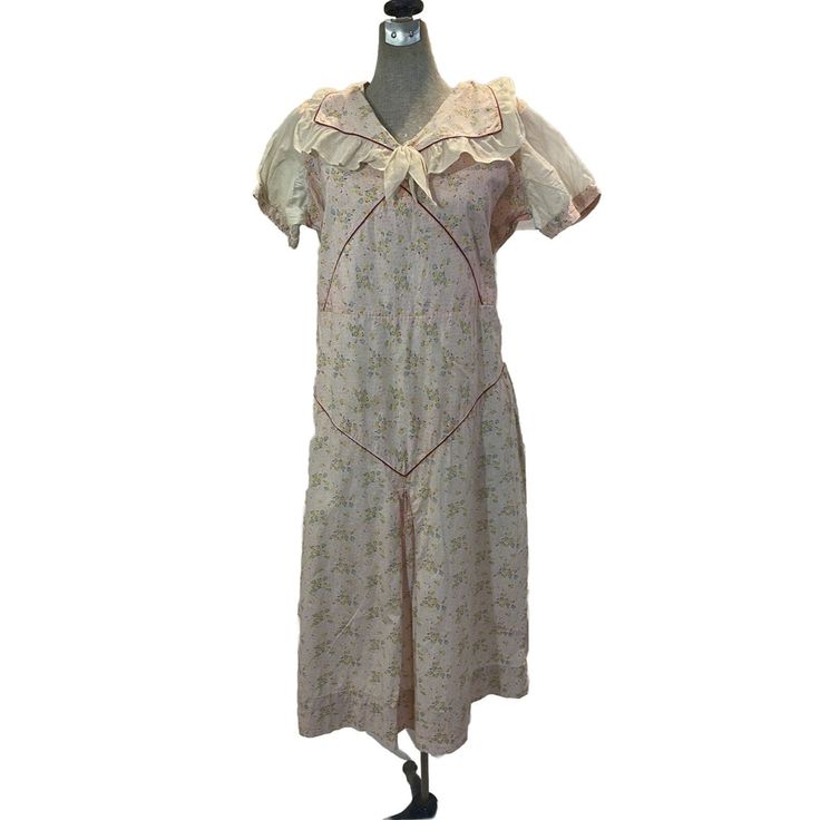 Vintage 1930s Fruit of the Loom dress. These are so hard to find and this is such a cute one! This one has a wide pilgrim collar made of cotton and ruffled voile trim. The sleeves are also a voile. At one point there was a self belt. Looking at this dress, you can see the seasons it's been through by the different colors on the original print. TEXTILE: cotton and voile LINING: none CLOSURE: slips over head LABEL: Fruit of the Loom ERA: 1930s MEASUREMENTS: BUST: 38'' WAIST: 36'' HIPS: 42'' LENGTH: 44'' Beige Vintage Dress With Ruffles And Short Sleeves, Cottagecore Cream Vintage Dress With Ruffles, Cottagecore Vintage Cotton Dress With Ruffles, Cottagecore Vintage Dress With Ruffles, Vintage Victorian Cotton Dress With Ruffles, Vintage Cotton Ruffle Dress For Daywear, Daywear Cotton Vintage Dress With Ruffles, Vintage White Ruffles Dress For Daywear, Vintage Puff Sleeve Dress For Daywear