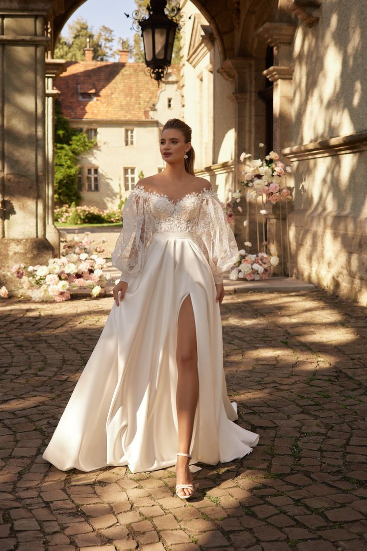 a woman in a white dress is standing on a brick walkway and posing for the camera