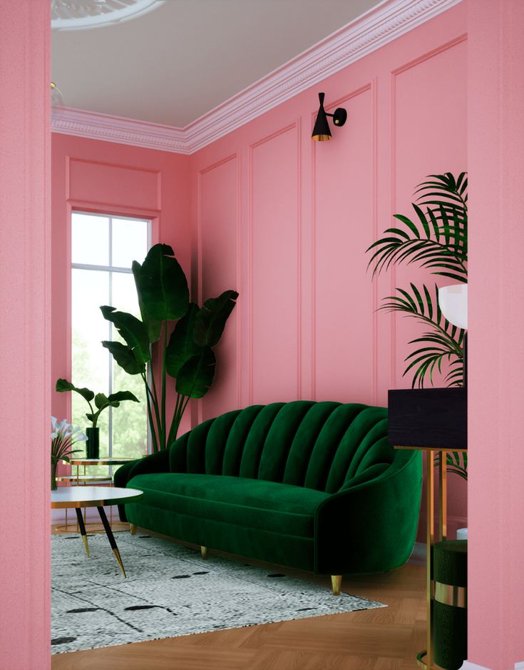 a living room with pink walls and green couches in the corner, along with potted plants