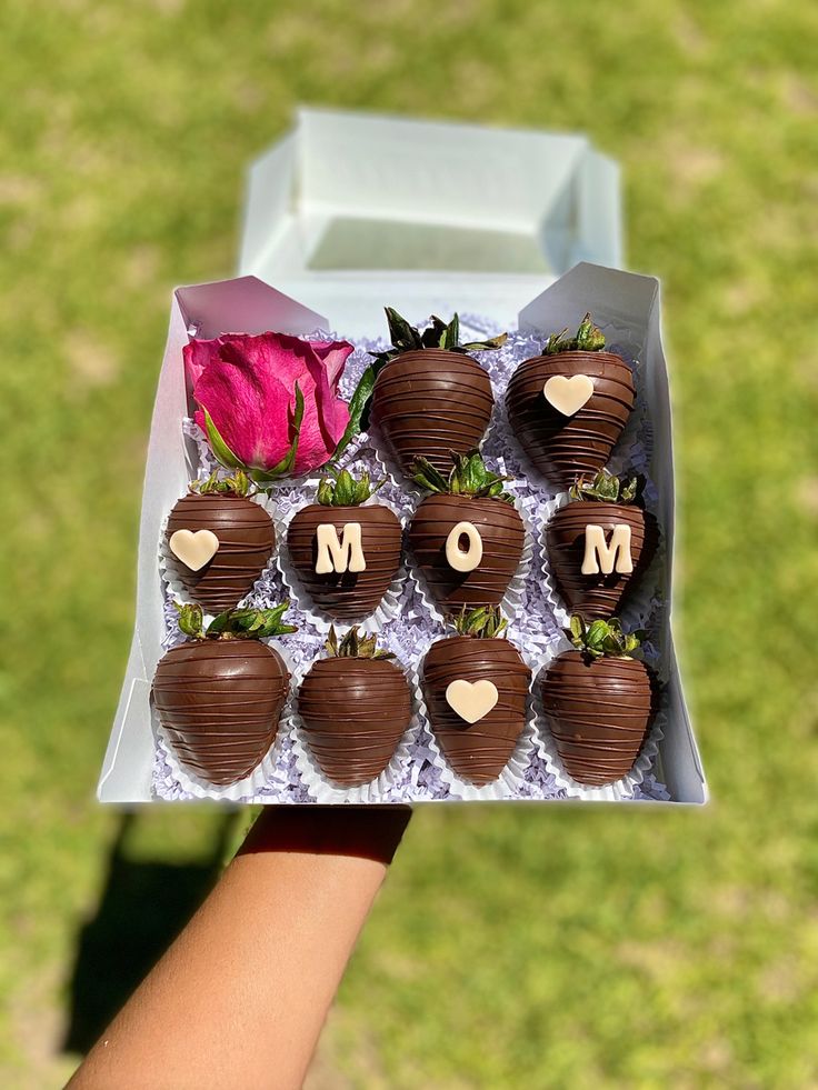 chocolate covered strawberries with the word mom written on them in front of a pink rose