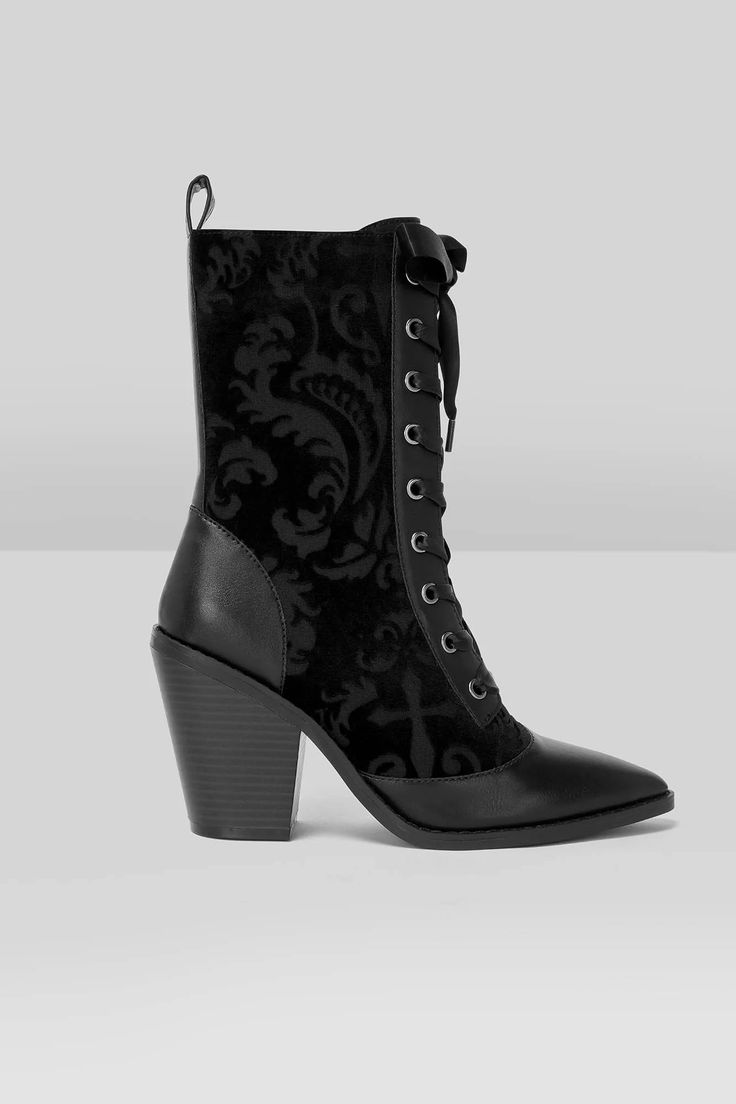 a pair of black lace up boots on top of a white surface with an ornate pattern