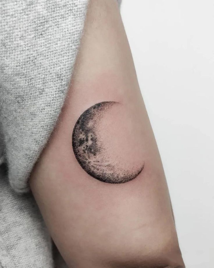 a woman's arm with a half moon tattoo on the left side of her arm