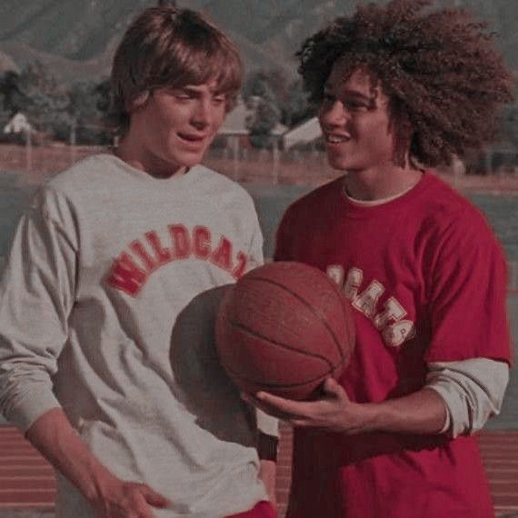 two young men standing next to each other holding a basketball