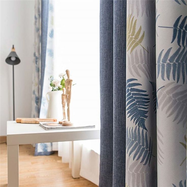 a living room with curtains and a table in front of the window that has a plant on it