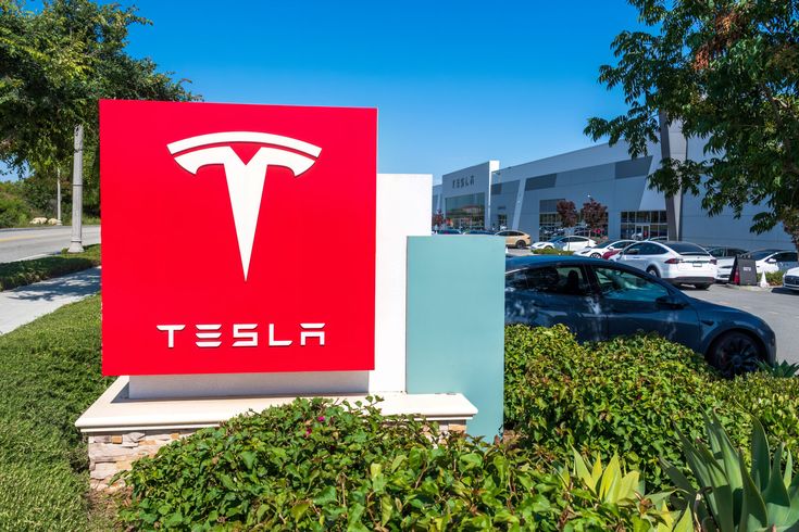 a red sign sitting in front of a car dealership