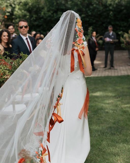 the bride is walking down the aisle with her veil over her head