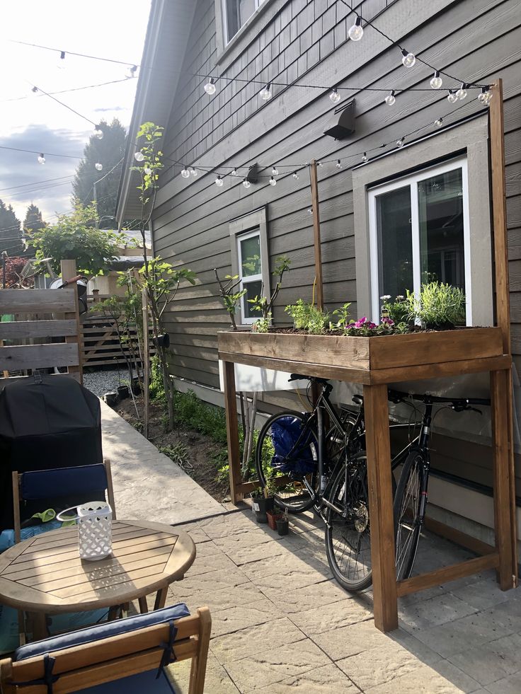 a bicycle is parked next to a table with flowers on it and lights strung from the roof