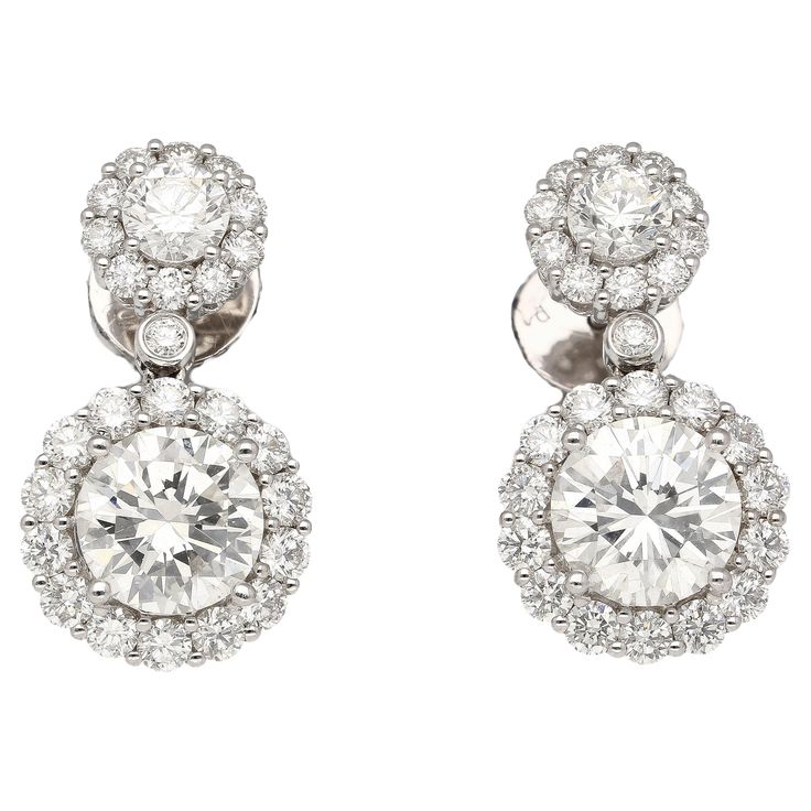 These drop earrings showcase a captivating duo of round diamonds, each boasting 1.51 and 1.50 carats. Graded H for near-colorless beauty and VS2 clarity, they sparkle with exceptional brilliance. Their elegance is further amplified by a sparkling halo, meticulously set with 50 round diamonds. Prong settings securely hold these precious stones, while the 18k white gold frame offers a touch of luxury. Butterfly backs closure ensure a comfortable and secure fit. Details:  ✔ Item Type: Drop Earrings ✔ Metal: 18k White Gold ✔ Weight: 4.98 grams ✔ Setting: Prong, Halo ✔ Closure: Butterfly back Stone Details (1): ✔ Gemstone: 2 Diamonds ✔ Carat: 1.51, 1.50 ✔ Color: H ✔ Cut: Round ✔Clarity: VS2 ✔ Measurements: 7.46 x 7.52 x 4.53 mm ✔ GIA Certificate #: 5161509015 Side Stone Diamonds: ✔ 2 round diam Gia Certificate, Halo Setting, Fit Details, Diamond Drops, 3 Carat, Diamond Drop Earrings, Gold Frame, Prong Setting, Fashion Earrings