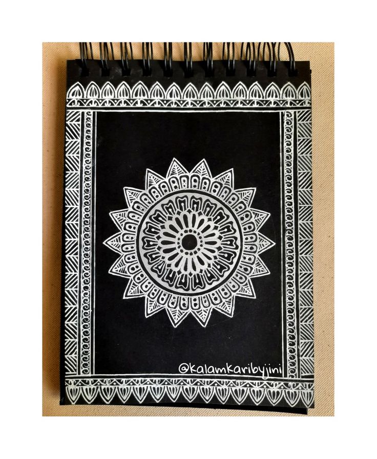 a black and white notebook with an intricate design on the cover, sitting on a table