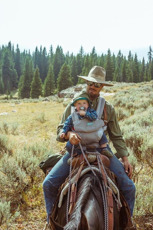 a man riding on the back of a brown horse next to a woman wearing a cowboy hat