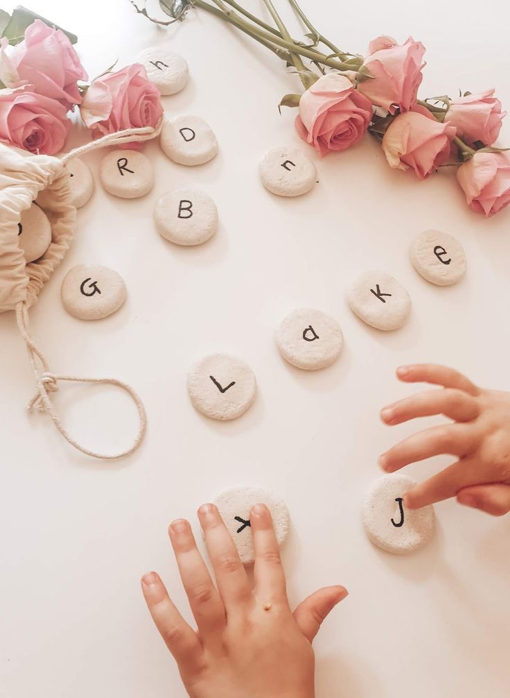 a child's hand reaching for rocks that spell out the letter j