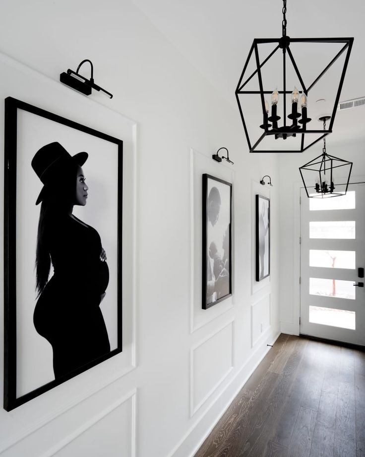 a black and white photo hangs on the wall next to two framed pictures, with a chandelier hanging from the ceiling