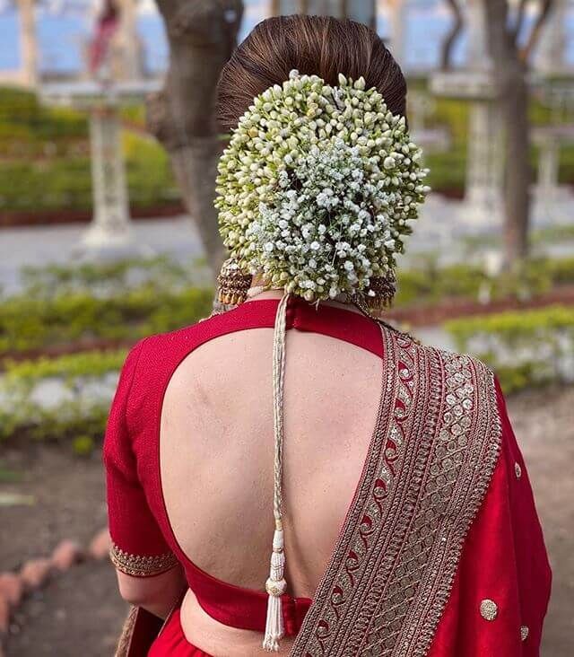 the back of a woman's head wearing a red sari with flowers on it