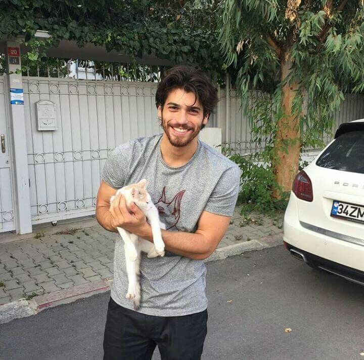 a man is holding a white cat in his hands while standing next to a car