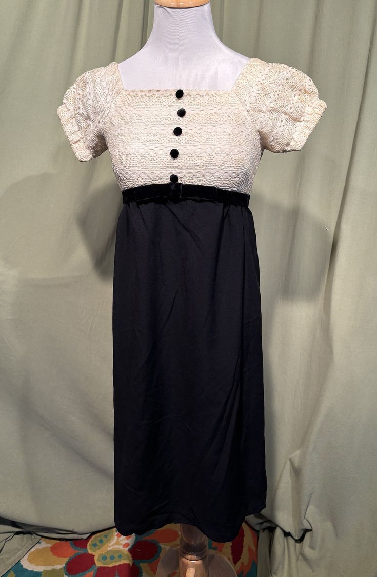 This is a cute vintage dress from the 60s.  Labeled Bobbie Brooks Petite Juniors. Made for those 5'1" and under. No size tags. The bust measures 30", empire waist 26", hip 36", see measurements below.  Made of a combination of black rayon & cream color lace. The dress is fully lined. It has puffy sleeves with elastic cuffs. The bodice back & sleeves are lace with a satin lining. The bodice is trimmed with velvet covered buttons & the Empire waist is accented with a velvet band & bow.  Zips in th Vintage Short Sleeve Evening Dresses, Retro Vintage Dress With Short Sleeves For Formal Occasions, Retro Dress With Buttons For Vintage Events, 1970s Style Fitted Vintage Dress For Vintage Events, Black Retro Dress For Vintage Events, Retro Vintage Dress With Buttons For Party, Black Short Sleeve Dress For Vintage Fashion, Vintage Black Dress For Daywear, Black Vintage Dress For Daywear