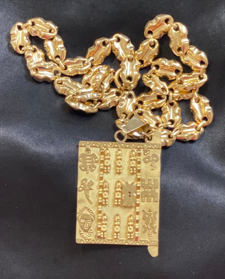 This handmade necklace is a stunning, unique piece of jewelry!  Weighing 50.1 grams (chain and pendant), the large size and beautiful shine of 18 karat yellow gold is an eye-catching conversation piece.  The peanut-style chain is 26 inches and the pendant is 1.75 in wide by 2.5 inches tall. Designed as a good luck/wealth charm in the style of an ancient African Dogon door, the pendant features a carved lock, warriors, animals, and spiritual symbols.  This necklace looks absolutely regal and would be a wonderful addition to your jewelry collection. Luxury Gold Rectangular Necklace, Luxury Gold Plated Necklace With Rectangular Pendant, Luxury Gold Plated Rectangular Pendant Necklace, Luxury Gold-plated Necklace With Rectangular Pendant, Gold Medallion Necklace For Good Luck, Traditional Yellow Gold Good Luck Necklace, Yellow Gold Chain Necklace With Square Pendant, Gold Necklace With Square Pendant Chain, Gold Plated Pendant Custom Necklace