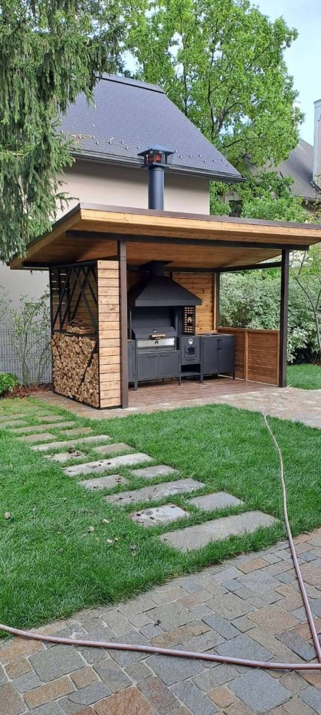 an outdoor living area with a grill in the center and grass on the ground next to it