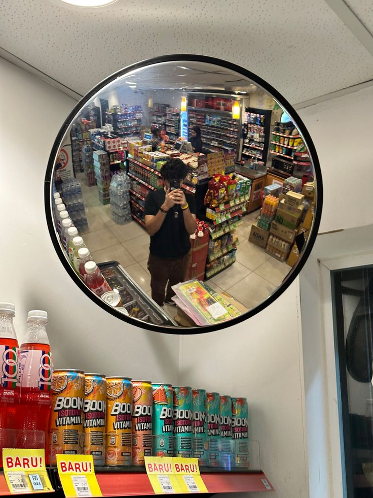 a man taking a selfie in front of a store's circular mirror on the wall