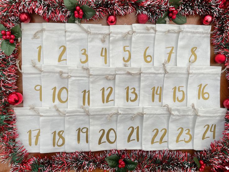 a christmas calendar hanging on a wall with red and green garlands around the numbers