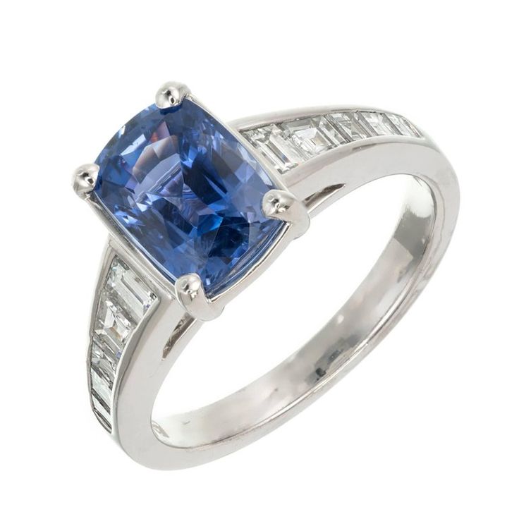 an engagement ring with a blue sapphire and baguets on the sides, set in 18k white gold