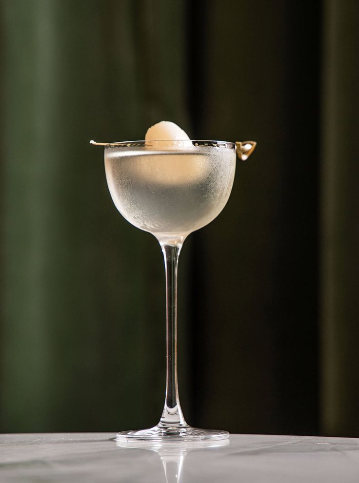 a martini glass with an olive garnish in it