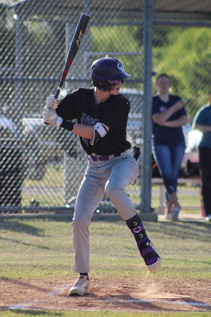 a young man holding a baseball bat on top of a field