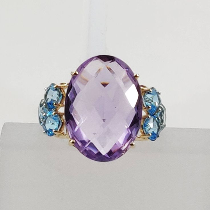 This stunning ring is set in 14k Solid Yellow Gold with Natural Purple Amethyst and Swiss Blue Topaz with utmost precision. It is an unique statement gemstone ring for nearly every occasion and is completely hassle-free jewelry. ITEM DETAILS * GEM: Purple Amethyst * GEM SIZE: 13X18 mm * GEM SHAPE: Oval Briolette * GEM: Swiss Blue Topaz * GEM SIZE: 4 mm (6pcs) * GEM SHAPE: Square Cushion cut * Total GEM WEIGHT: 13.00 carats * Gold Purity: 14KT * Gold Weight: 1.77 gram * Total Weight of the Ring: Formal Purple Topaz Gemstone Ring, Elegant Blue Multi-stone Amethyst Ring, Blue Multi-stone Amethyst Ring As Gift, Blue Amethyst Ring With Accent Stones, Fine Jewelry In Blue Amethyst, Luxury Blue Amethyst Gemstone Ring, Fine Jewelry Blue Amethyst Jewelry, Blue Amethyst Multi-stone Jewelry, Blue Amethyst Gemstone Ring