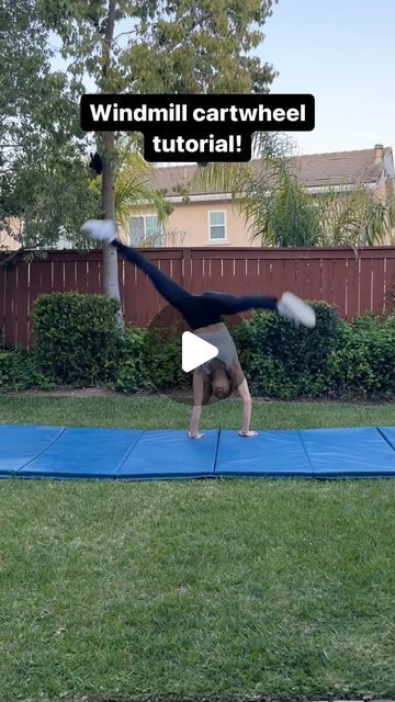 a person doing a handstand on a blue mat in front of a house