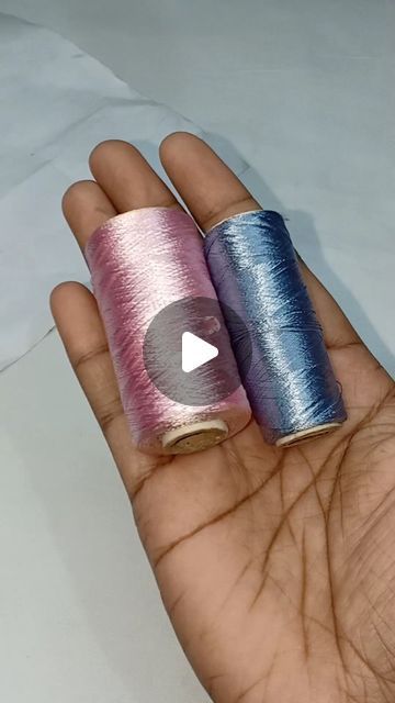 two spools of thread sitting on top of each other in someone's hand