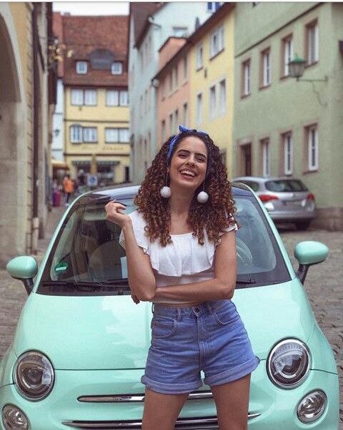 a woman standing in front of a blue car