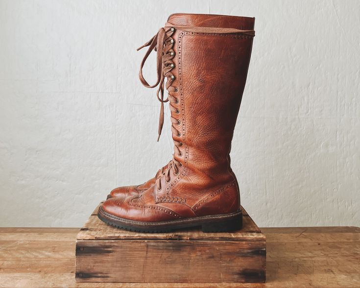 ꞊ Extraordinarily rare Cole Haan 1930's style knee high lace up boots in warm whiskey brown. ꞊ Thick solid leather, beautifully made. ꞊ Wingtip detailing. ꞊ brass grommets and textured sole. ꞊ Condition is good with minor creasing, a few scuffs/scratches on the toe and shaft, grommet patina, and some slight discoloration to laces from the grommets. I might replace the laces with waxed cord to make them easier to lace/unlace but the ones they have work fine. ||   M E A S U R E M E N T S   || Labeled As: 8B Fits Like: true to size with thin socks Ball: 4" sole: 10.75" Heel: 1.25" Total Height: 15" Vintage Fitted Boots With Laces, Vintage Fitted Lace-up Boots For Fall, Fitted Vintage Lace-up Boots For Fall, Vintage Leather Knee-high Lace-up Boots, Vintage Wide Calf Knee-high Boots, Vintage Brown Knee-high Boots, Vintage Knee-high Boots, Vintage Knee-high Lace-up Boots For Fall, Vintage Boots With Laces For Fall