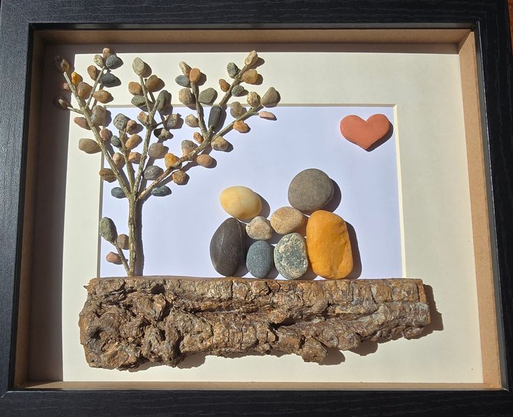 a shadow frame with rocks and a tree in it that is made to look like two people sitting on a log