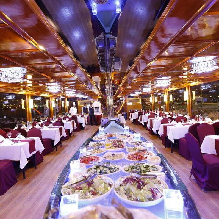 a long table filled with lots of food on top of a wooden floor covered in purple cloths