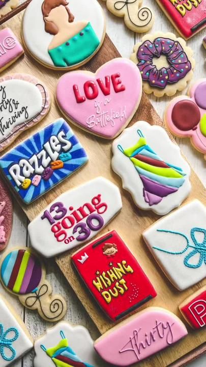 decorated cookies are displayed on a wooden board with words and pictures in the middle, along with other cookie decorating items