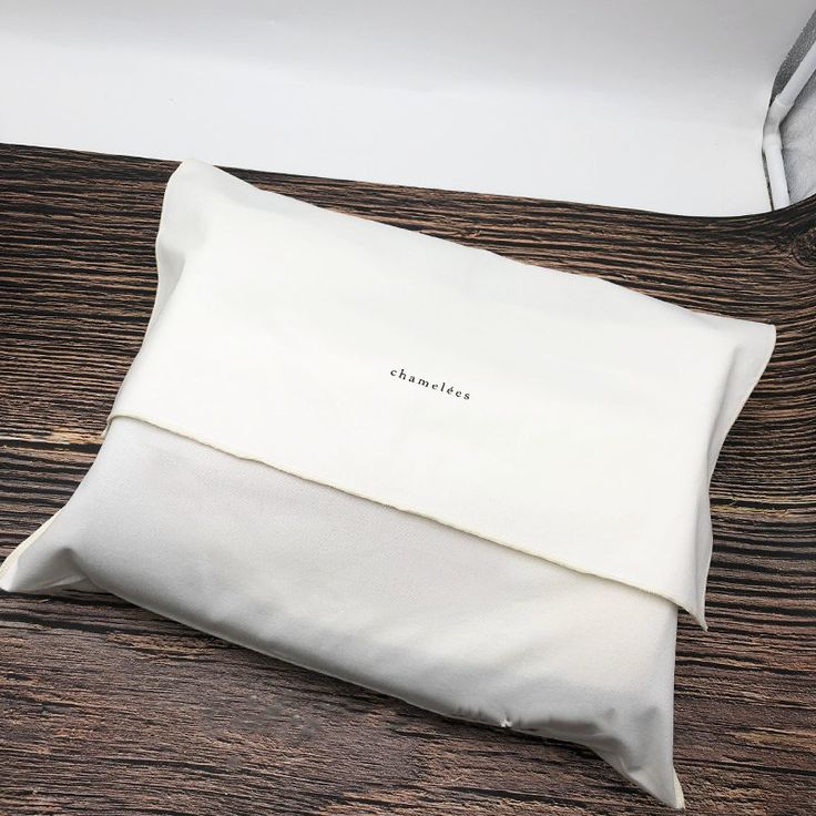 a white pillow sitting on top of a wooden table next to a box with an envelope