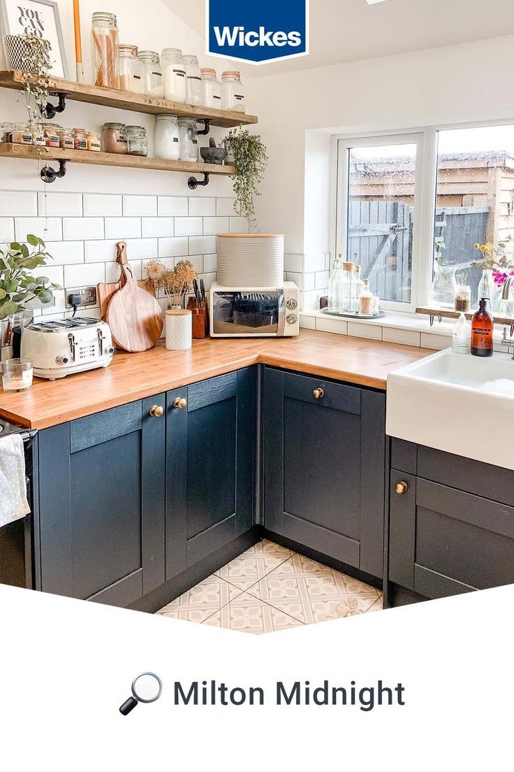 a kitchen with blue cabinets and wooden counter tops, white tiles on the wall and open shelving above