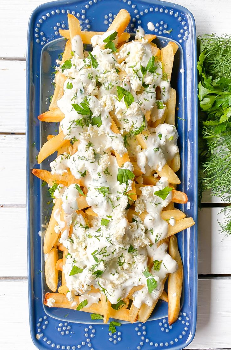 a blue plate topped with french fries covered in cheese