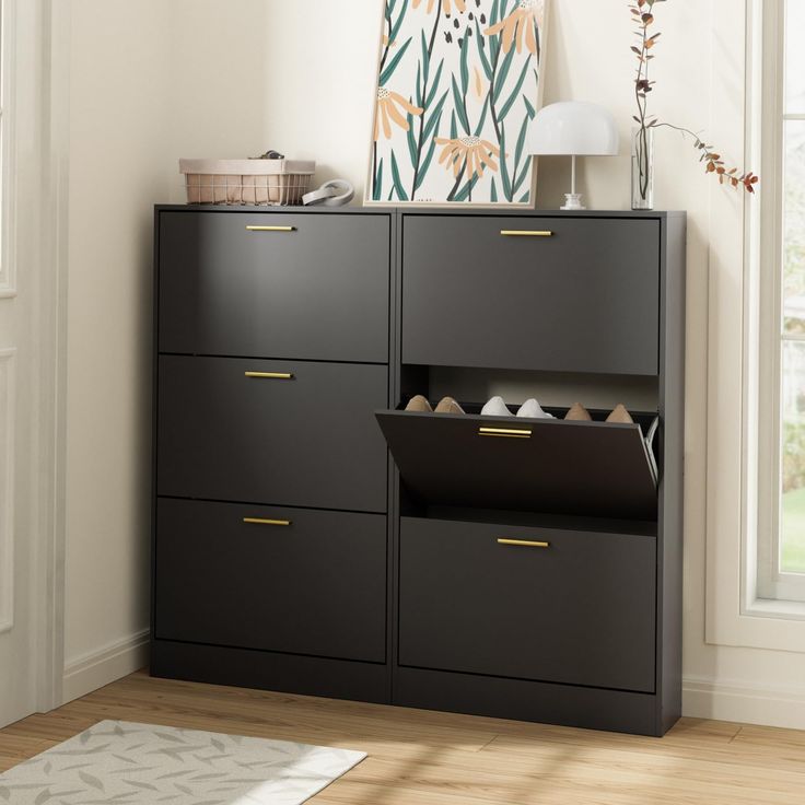 a black cabinet with two drawers and some shoes on the bottom shelf next to it