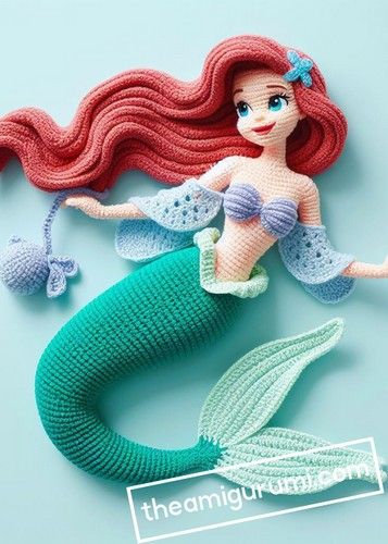 a crocheted mermaid doll with red hair and blue tail sitting on top of a table